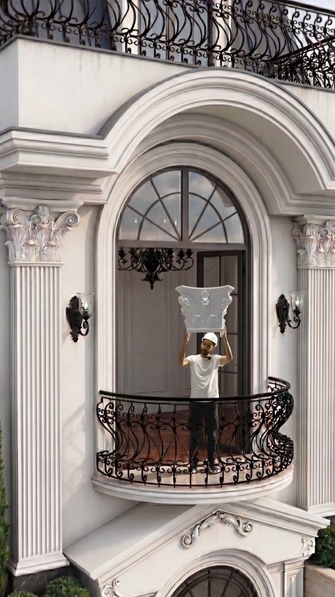 Dekoratif sütun başlığı ferforje balkon korkuluğunun ardında yukarıda tutuluyor