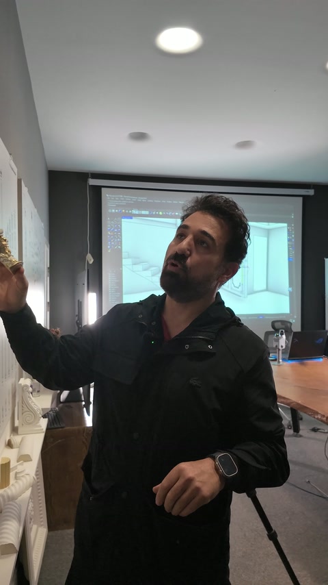 Sunucu, elindeki süslü sütun başlığını ürün panosu önünde tanıtıyor.