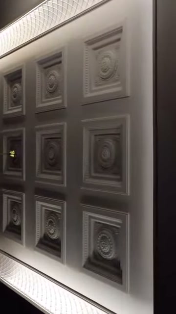 Beyaz tavan yüzeyinde farklı boyutlarda kabartmalı kare modüller bulunuyor