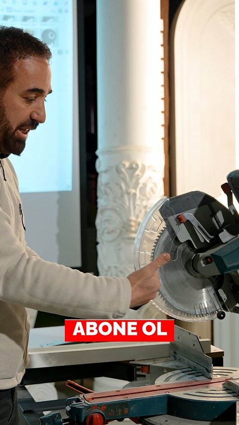 Usta, kesim makinesi yanındaki profil numunesinin kenarını işaret ediyor