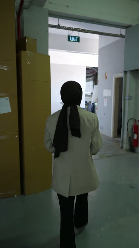 Büyük kolilerin yanındaki üretim koridorunda fabrika içi hareketlilik görülüyor