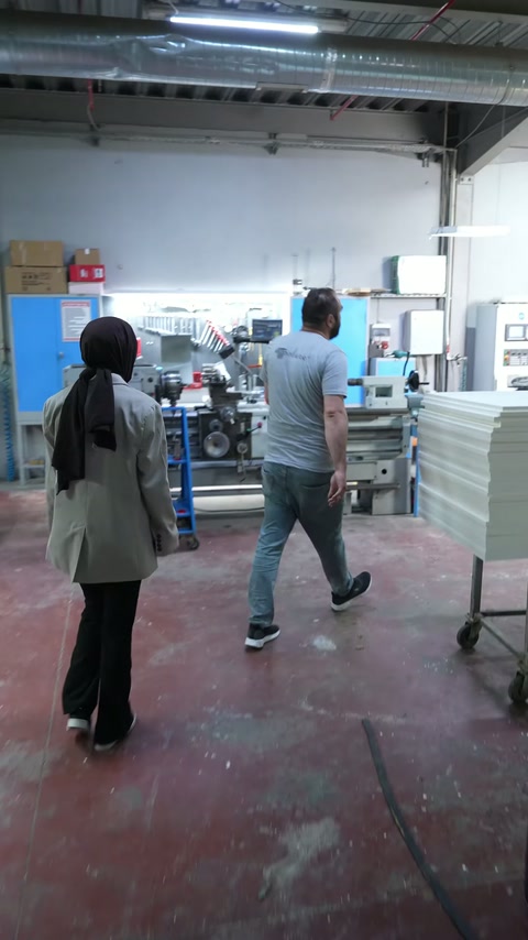 CNC bölümünde iki çalışan, makinelerin bulunduğu alana birlikte giriyor