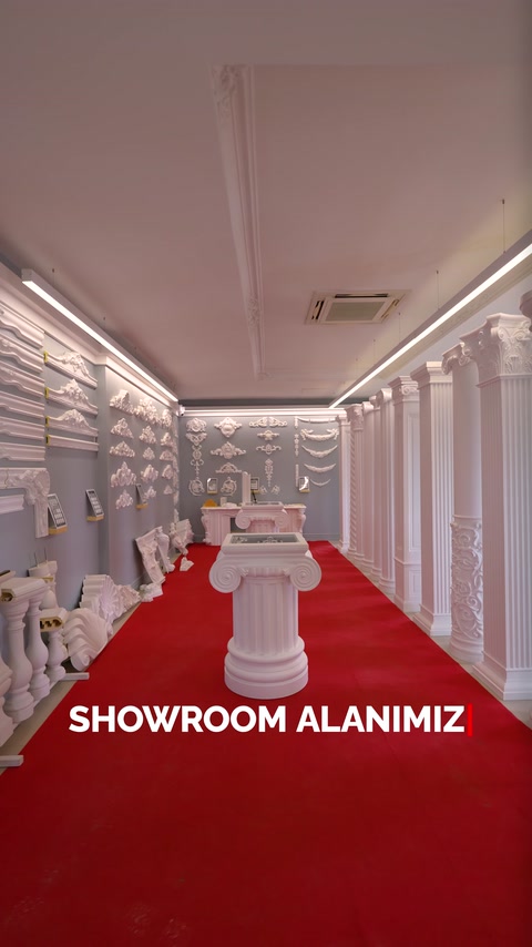 Kırmızı halılı showroomda sütunlar, kaideler ve duvar süsleri