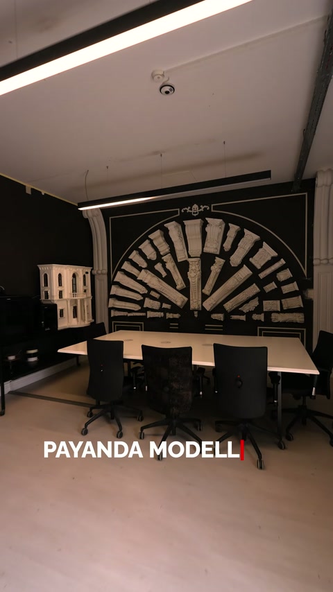 Toplantı masasının arkasında yarım daire biçiminde payandalar sergileniyor