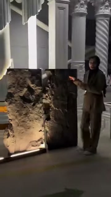 Görevli, yan yana duran iki dekoratif paneli eliyle tanıtıyor