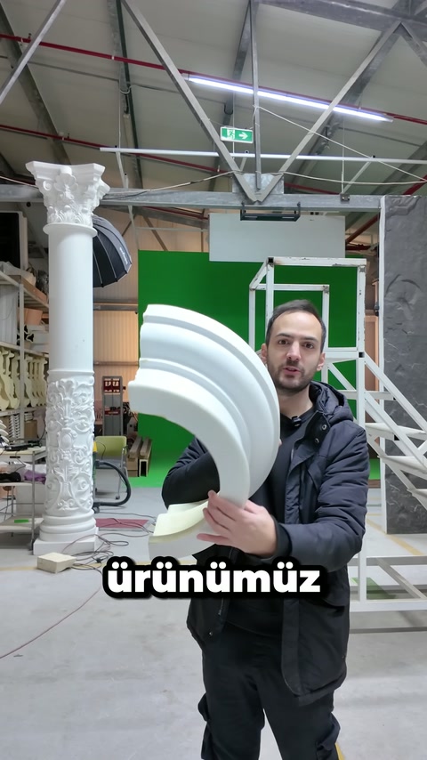 Atölyedeki usta kalın kavisli dekoratif profili iki eliyle sergiliyor