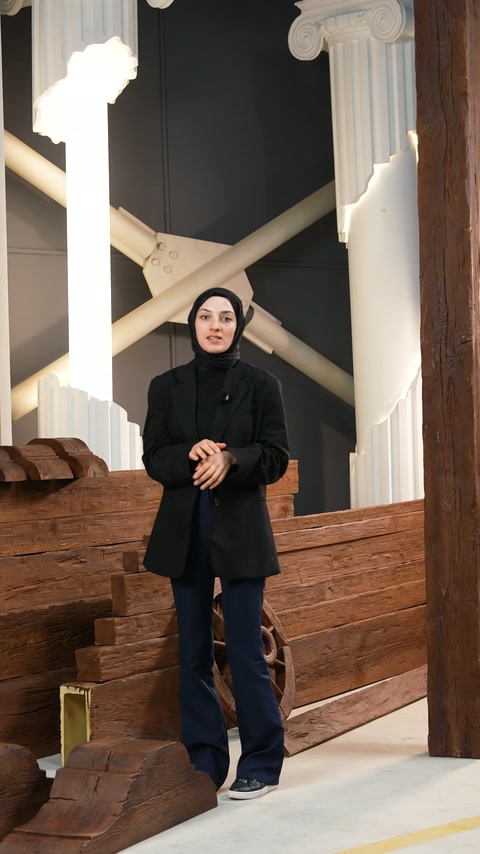 Sunucu, dik kiriş ve payandaların önünde koleksiyonu anlatıyor