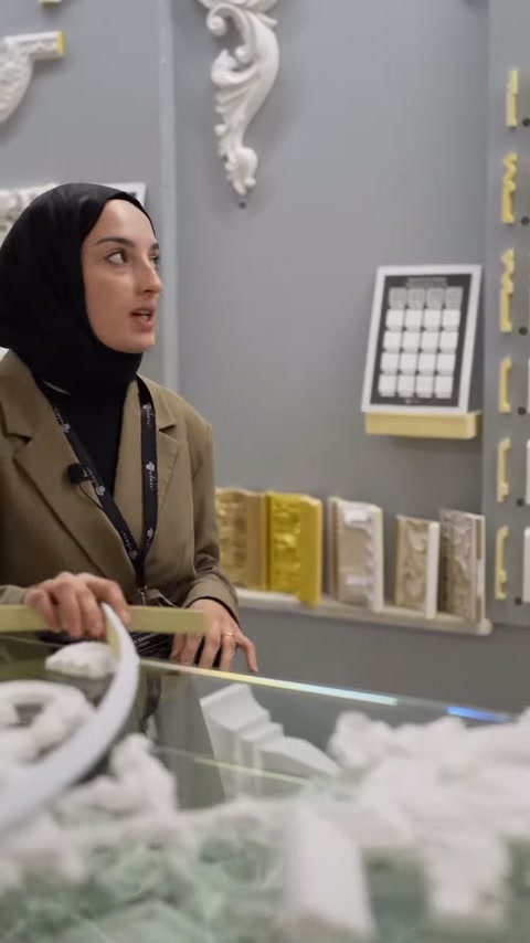 Sunucu duvardaki kabartmalı köşe modellerine doğru bakıyor.