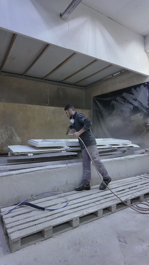 Atölyede sıralanan beyaz panellere püskürtme boya uygulanıyor.
