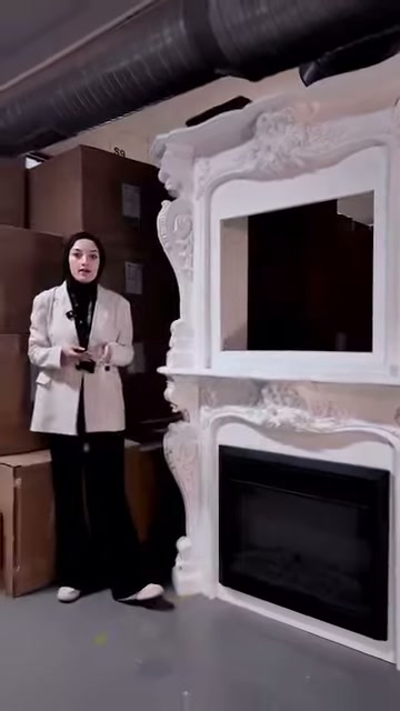 Sunucu geniş çerçeveli şöminenin önünde ellerini birleştirerek konuşuyor