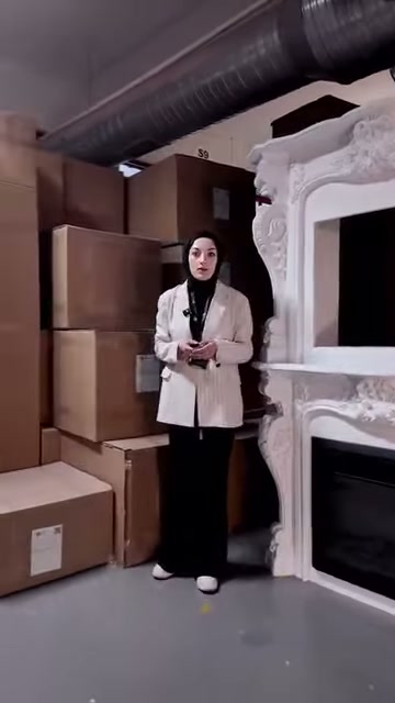 Çiçekli kabartmalarla süslü şömine çerçevesi sunucuyla birlikte görülüyor