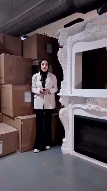 Sunucu işlemeli beyaz şöminenin yanında ürün özelliklerini anlatıyor