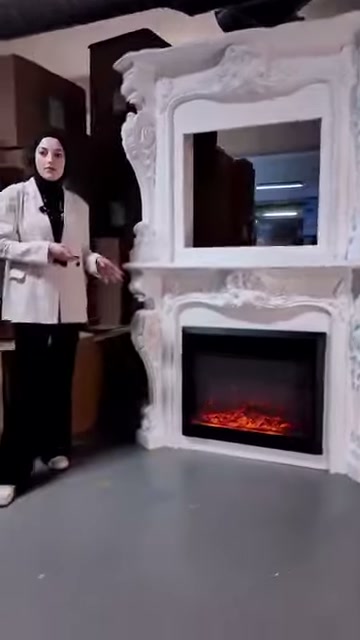 Sunucu kırmızı alev efektli şöminenin yanında açıklama yapıyor