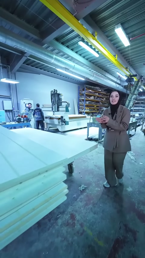 İstiflenmiş panel ürünleri sunucunun arkasında düzenli şekilde duruyor