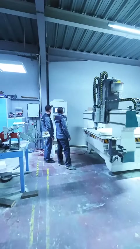 Sunucu ve çalışanlar büyük CNC makinesinin önünde bir araya geliyor