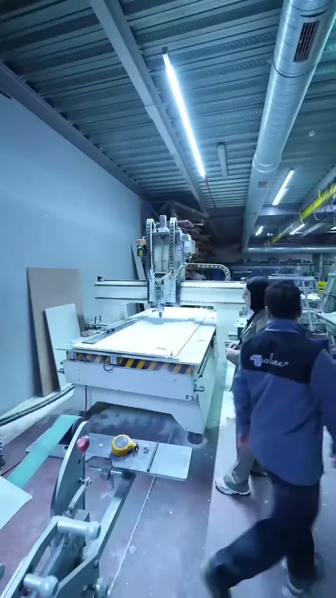 Sunucu CNC tezgâhının önünde üretim personeliyle birlikte duruyor