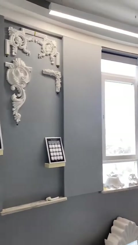 Pencere yanındaki gri panoda klasik kabartmalı duvar motifleri sergileniyor.