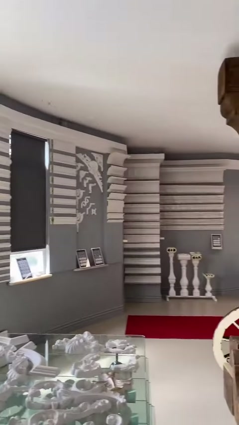 Geniş sergi alanında profil panoları ile cam numune masası görülüyor.