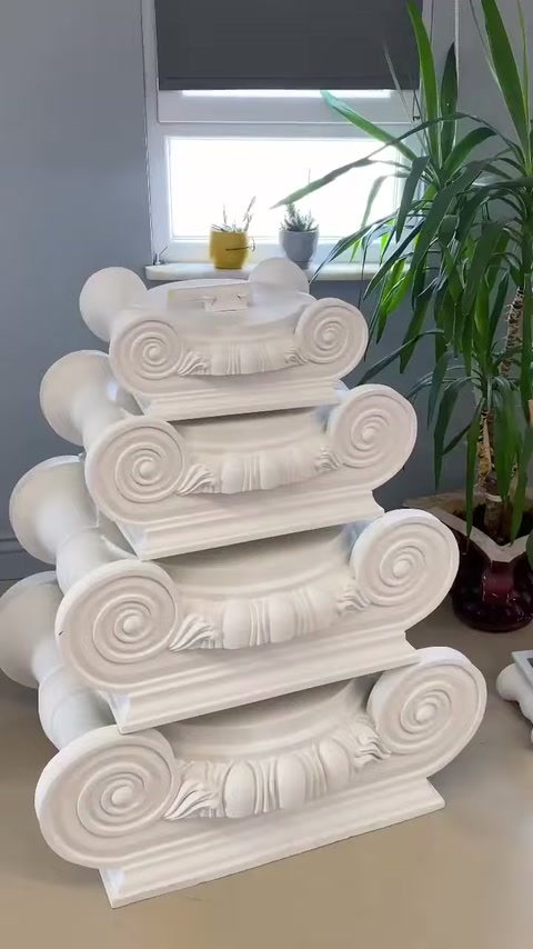 Pencere önünde üst üste konmuş volütlü sütun başlıkları sergileniyor.