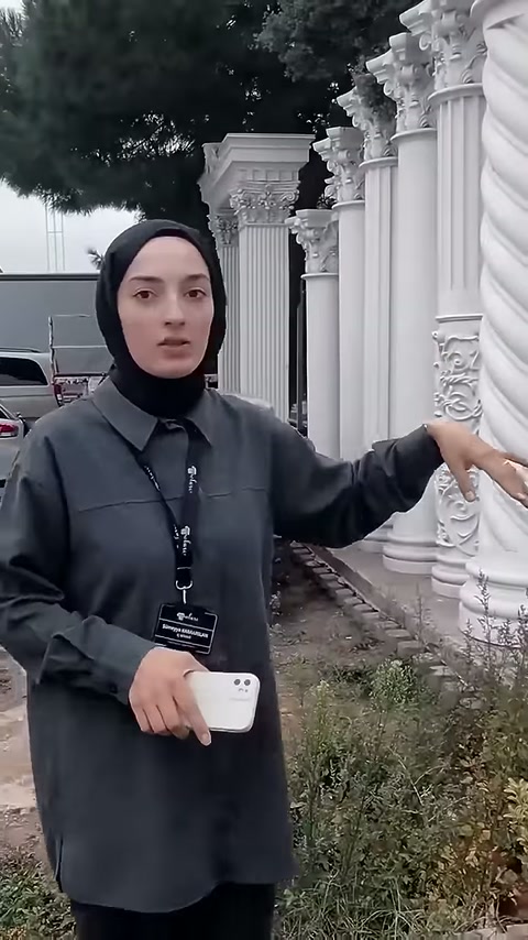Sunucu, burgulu sütunun kabartmalı alt bölümüne eliyle dokunuyor.