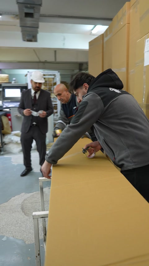 Çalışanlar büyük karton kutuyu sevkiyat için hazırlıyor