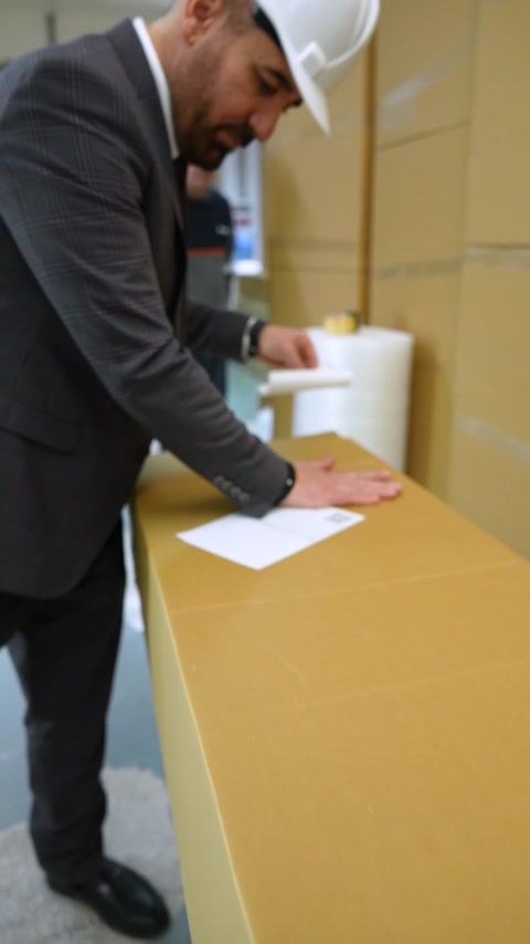 Paketleme masasında kapatılan büyük karton sevkiyat kolisi görülüyor