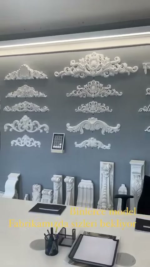 Toplantı masasının arkasında çok sıralı dekoratif motif koleksiyonu bulunuyor