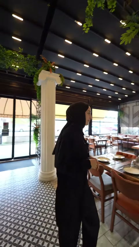 Sunucu, restoran salonundaki beyaz sütunun dekoratif yüzeyini inceliyor.