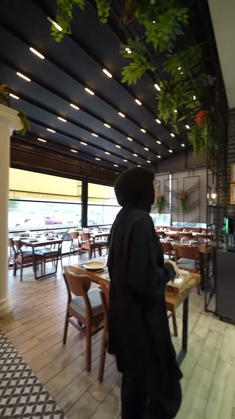 İyon sütun geride kalırken restoranın masa düzeni görüntüleniyor.