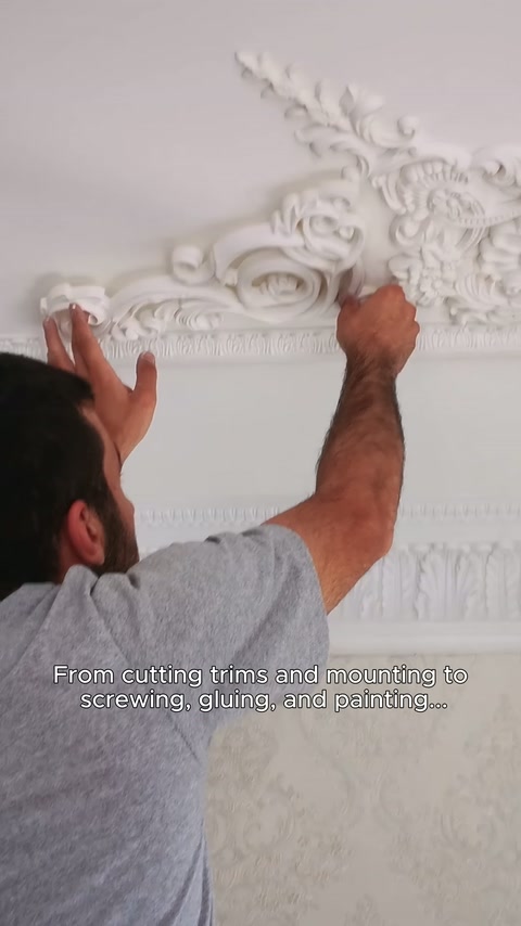 İşlemeli kartonpiyer parçası duvarın tavan birleşimine elle yerleştiriliyor.