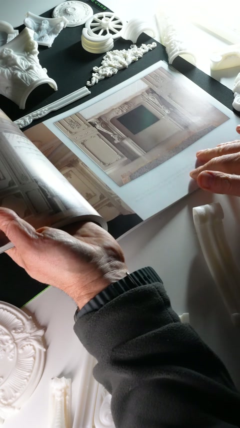 El, katalogdaki tavan ve duvar bezemelerinin yerleşimini işaret ediyor