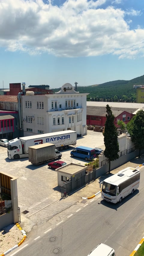 Üretim binası, park alanı ve kamyonlar aynı karede yer alıyor