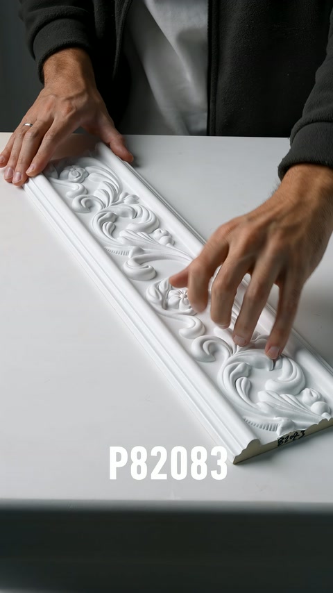 Beyaz işlemeli bordürün tekrarlanan çiçek desenleri parmaklarla izleniyor