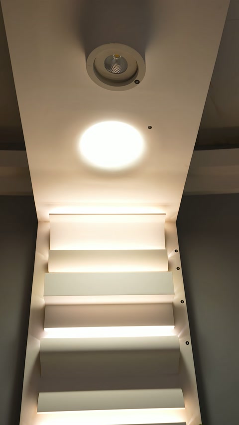 Merdiven tavanındaki yuvarlak amorf armatür, basamaklarla birlikte görüntüleniyor.