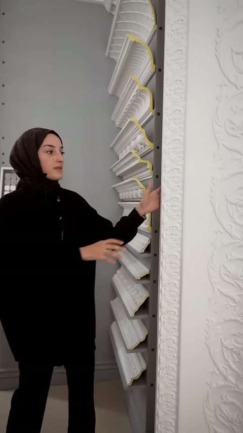 Sunucu, dikey sergilenen motifli dekoratif panelin yüzeyine dokunuyor.