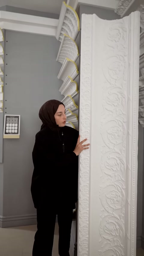 Sunucu, geniş kabartmalı panel üzerindeki bitkisel motifleri eliyle gösteriyor.