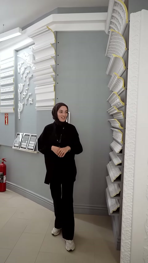 Sunucu, tavan uygulamalarıyla çevrili teşhir alanında ürünleri tanıtıyor.