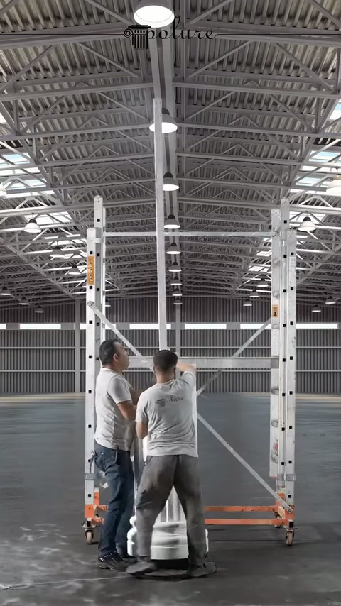 Çalışanlar, uzun sütun parçasını iskele önünde dik tutuyor.