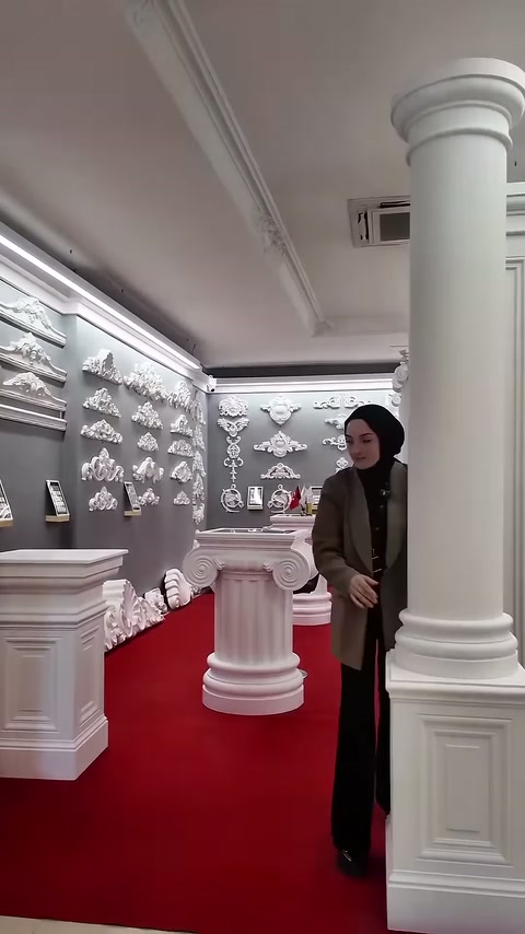 Sunucu geniş gövdeli sütunun arkasında durarak modeli sunuyor
