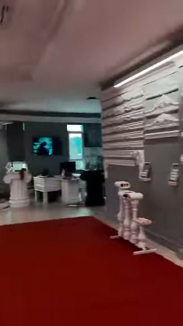 Showroom salonunda kırmızı halı, masalar ve duvar profilleri bulunuyor
