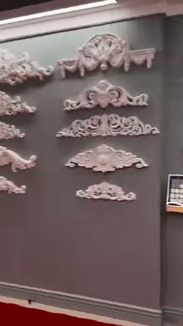 Gri pano üzerinde simetrik kabartmalı alınlık süsleri sıralanıyor