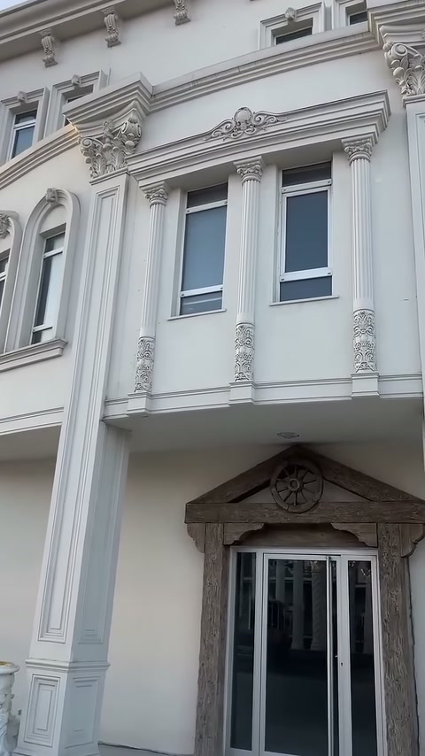 Üst kattaki pencereler, ince dekoratif sütunlar ve kabartmalı başlıklarla çevreleniyor