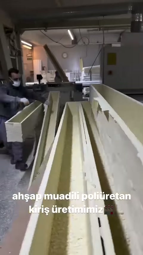 İşçi uzun kirişleri üretim hattı üzerinde yan yana düzenliyor.