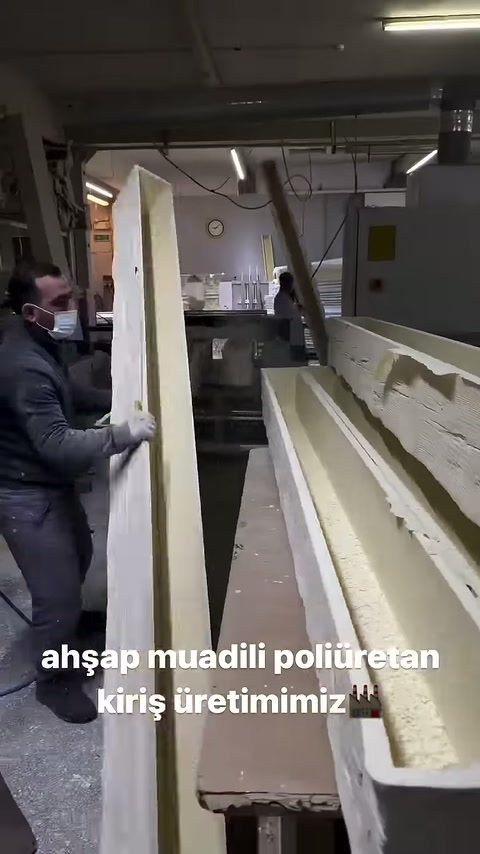 Çalışan dik tuttuğu poliüretan profili tezgâha doğru indiriyor.