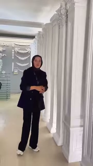 Tanıtıcı, yüksek sütunların oluşturduğu showroom sırasının önünde duruyor.