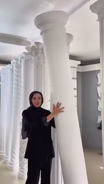 Tanıtıcı, pürüzsüz beyaz sütunun kalın gövdesini iki eliyle gösteriyor.