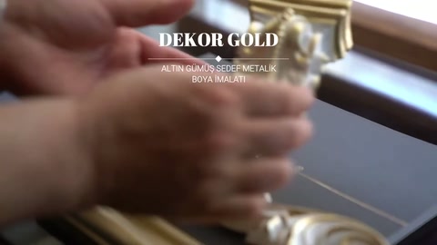 Altın boyalı işlemeli köşe elemanı elde çevrilerek yüzey detayları gösteriliyor.