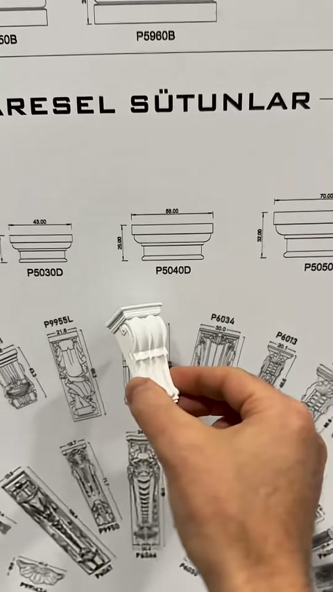 Kademeli beyaz payanda parçası katalog tasarımları önünde inceleniyor