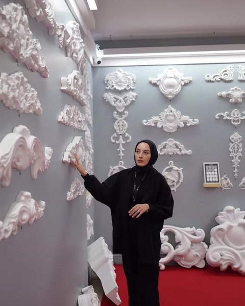 Sunucu, duvar üzerindeki farklı boyutlardaki dekoratif taçları işaret ediyor.