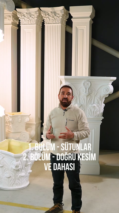Sunucu, dekoratif sütun başlıkları önünde elleriyle ayrıntıları açıklıyor.